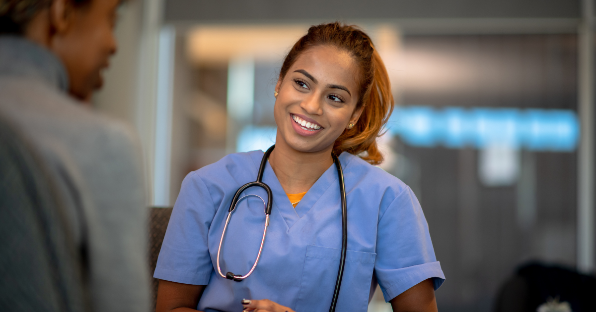 Nurse speaking with a patient in a clinical setting, representing wound care medical device use for venous leg ulcers (VLU)..